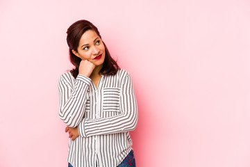 Middle age latin woman isolated on a pink background who feels sad and pensive, looking at copy space.