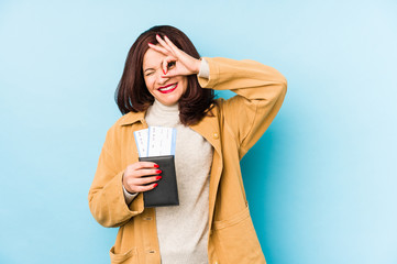 Middle age latin woman holding a passport isolated excited keeping ok gesture on eye.