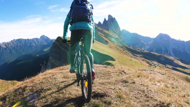 Young man with mountain bike cycling on Seceda mountain peak at sunrise. Puez Odle, Trentino, Dolomites, Italy.