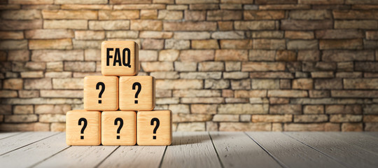 cubes with the abbreviation FAQ in front of a brick wall on wooden floor
