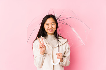 Young chinese woman holding a umbrella isolated showing number two with fingers.