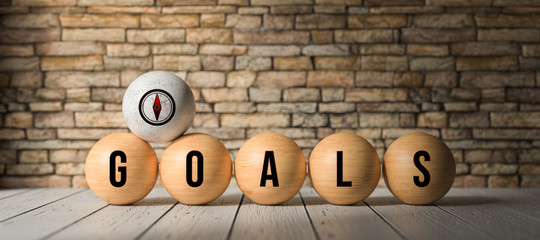 wooden balls with word GOALS in front of a brick wall on wooden background