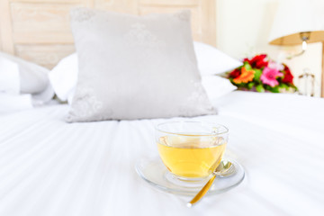 Herbal tea on bed linen in the upscale hotel room. Being alone, getaway, staycation, digital detox concepts. Horizontal