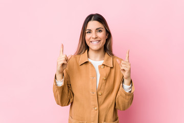 Young caucasian woman isolated indicates with both fore fingers up showing a blank space.