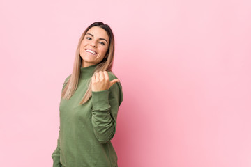 Fototapeta premium Young caucasian woman isolated points with thumb finger away, laughing and carefree.