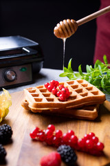 Topping golden Belgium waffles with fresh fruits and honey.