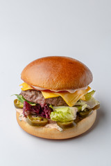 Juicy beef burger with cheddar, cucumber and jalapeno isolated on white background