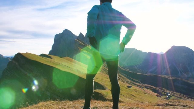 Young man in sport trail clothes running on Seceda mountain peak at sunrise. Puez Odle, Trentino, Dolomites, Italy.