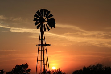 Kansas colorful Sunset with clouds and a Windmill Silhouette out in the country.