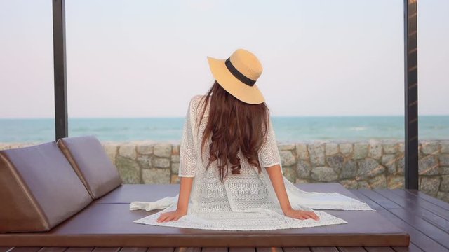 Young beautiful women sitting and relaxing on the beachside resort with a beautiful view of the endless ocean in the background.