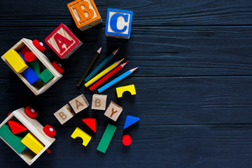 Wooden blocks with A B C letters, train, toys for creativity development on black background. Educational games for kindergarten, preschool kids.