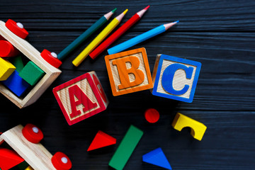 Wooden blocks with A B C letters, train, toys for creativity development on black background. Educational games for kindergarten, preschool kids.