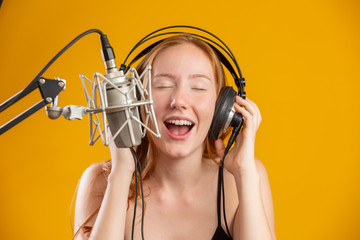 Beautiful redhead woman face singing with a condenser silver microphone open mouth performing song...