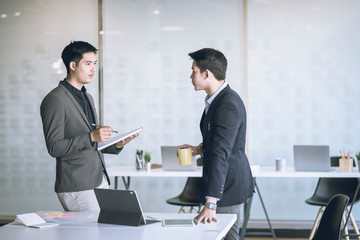 Business people talking during coffee break in modern office or coworking space. Young Asian business relaxing after working time.