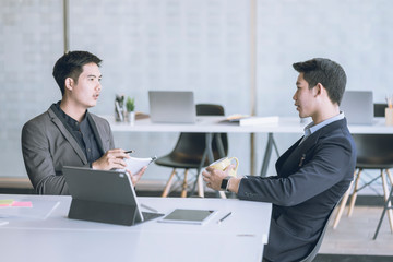 Business people talking during coffee break in modern office or coworking space. Young Asian business relaxing after working time.