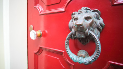 Ornate door knocker in Beacon Hill, Boston, Massachusetts on a red door.
