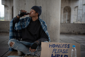 Homeless with dirty hands drinking alone