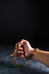 Faith in Islam,hand holding rosary beads on dark background. Islamic holiday celebration Eid Mubarak or Ramadan Kareem concept. Copy space.