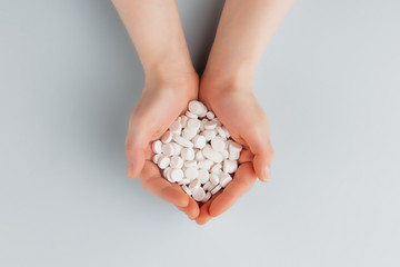 Obraz premium Round white pills on the palm of a female top view, overdose of pills. Copy space. Pharmacy and medical concept