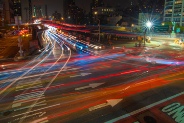 Busy traffic entering and exiting the Ed Koch Queensboro bridge at night leaving light streaks.