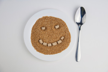 Fibers powder  lying on white dish on white background near lie chrome spoon and fork smile on fibers powder with pressed bran