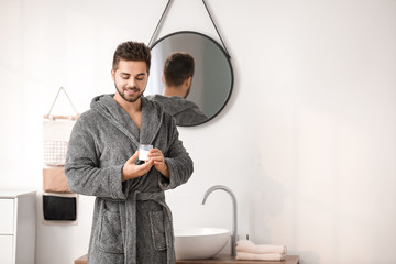 Handsome young man with cosmetic cream in bathroom