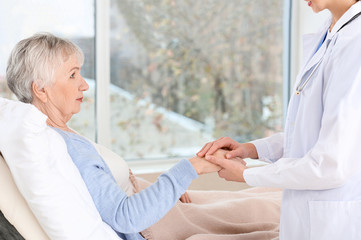 Fototapeta premium Female doctor with senior woman suffering from Parkinson syndrome in clinic