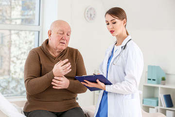 Obraz premium Female doctor working with senior man suffering from Parkinson syndrome in clinic