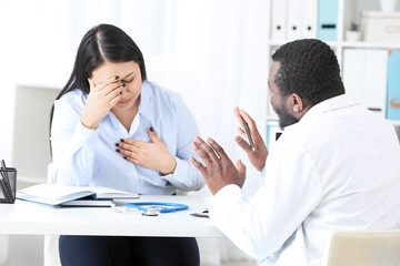 Fototapeta premium Young woman visiting male cardiologist in clinic