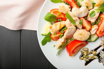 Plate with tasty chicken salad on table
