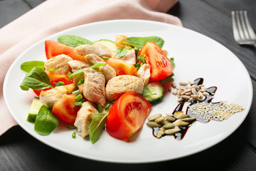 Plate with tasty chicken salad on table