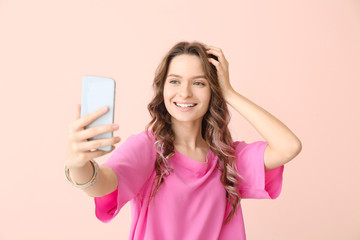 Naklejka premium Young woman taking selfie on color background