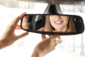 Driver adjusting rear view mirror in car