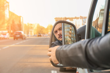 Driver adjusting side mirror of modern car