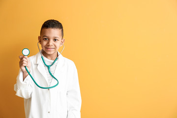Cute little African-American doctor on color background