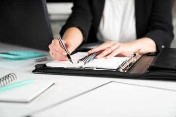 Fototapeta premium Office work. Cropped image of female employee working in office, supplies on tabletop.