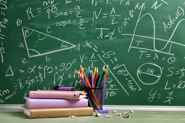 Set of school supplies on table near blackboard