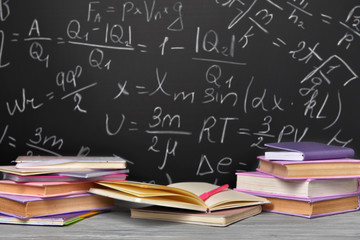 Books and copybooks on table near blackboard
