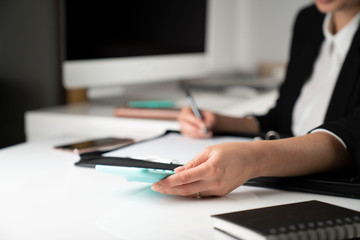 Office work. Cropped image of female employee working in office, supplies on tabletop.