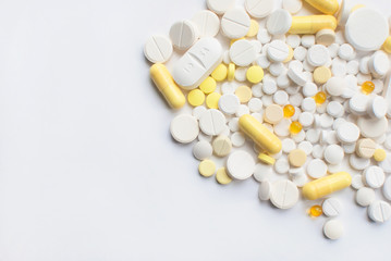 A bunch of yellow and white tablets and pills isolated on a white background close up.