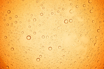Rain droplets on yellow glass background, Water drops on yellow glass.