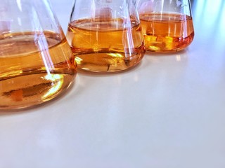 The Erlenmeyer or Conical flask on bench laboratory, with gradient solvent for analysis concentration range of iron show the orange color compound, detect with UV-spectrophotometer in waste water.