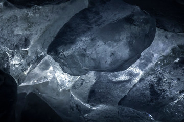 Pieces of cold ice with blue backlight closeup.