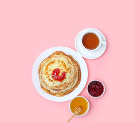 Pancakes, Cup of tea and sweets - honey, jam on pink background. Pancake week, Maslenitsa concept. delicious Breakfast with Homemade Pancakes. flat lay