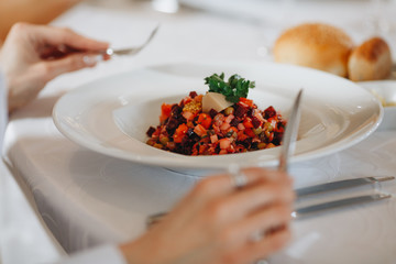 Man eats venegret salad in restaurant on white plate close-up