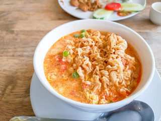 A white bowl of delicious instant noodle curry's tast cooked on wooden table, closeup image with...