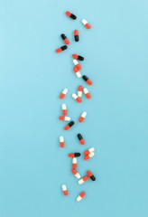 Colorful medical capsules on blue  background top view.
