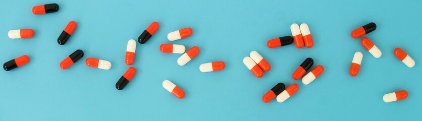 Colorful medical capsules on blue  background top view.banner