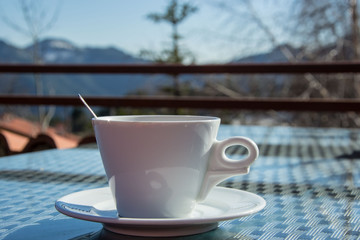 A cup of coffee outdoors, close-up of a hot beverage and mountain in the background