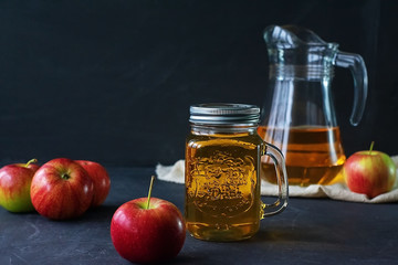 Glass jar of juice and jug with fresh fruits on a dark background. Summer refreshing drink